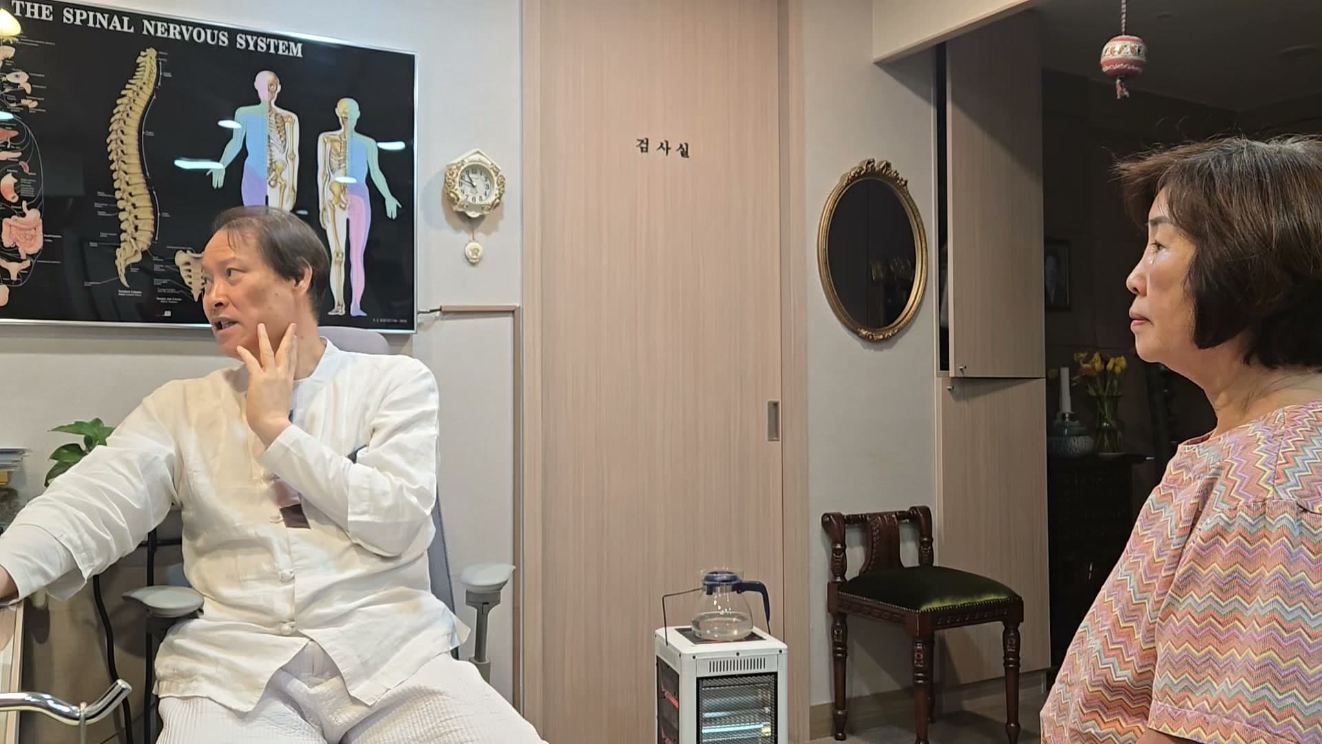 진료실에서 의료진과 환자가 전신 가려움과 피부 상태의 경과에 관해 이야기하는 장면