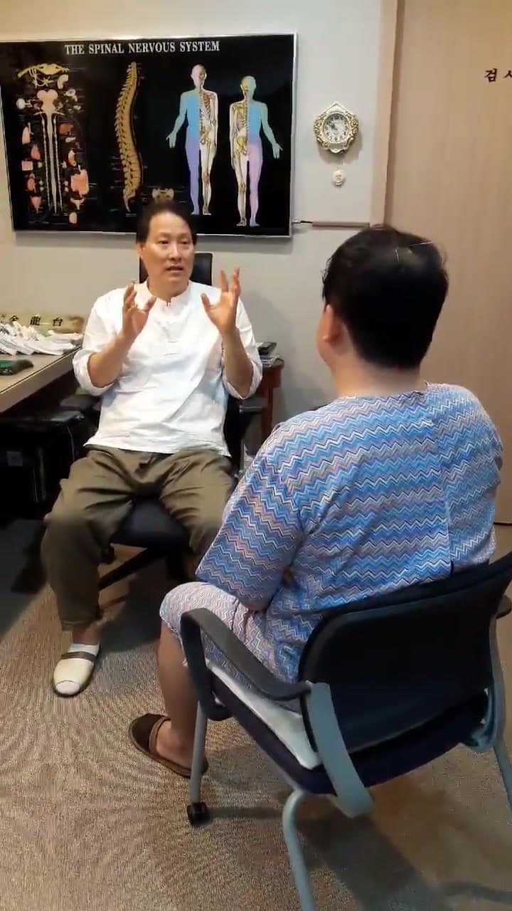 진료실에서 의료진과 환자가 강직성척추염으로 인한 등과 고관절 및 발목 불편을 상담하는 장면