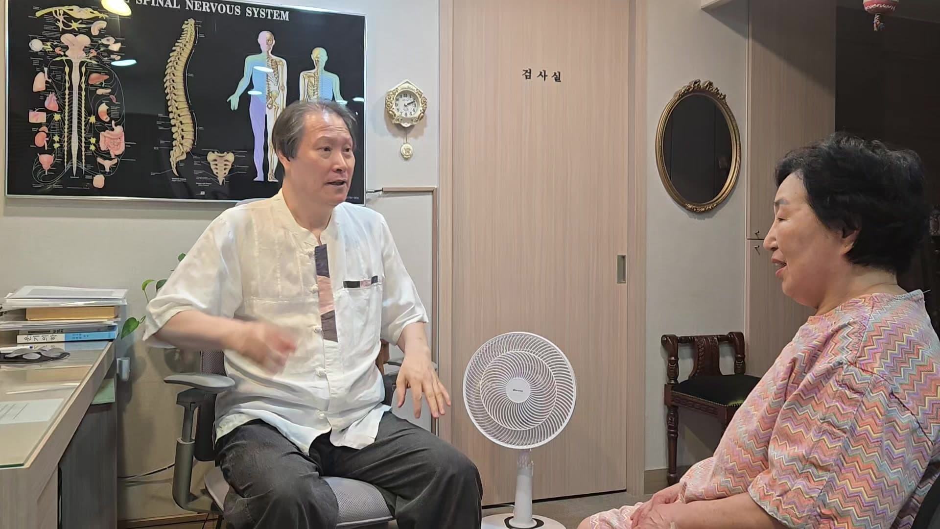진료실에서 의료진과 환자가 오래된 허리 통증과 보행 불편에 관해 이야기하는 장면