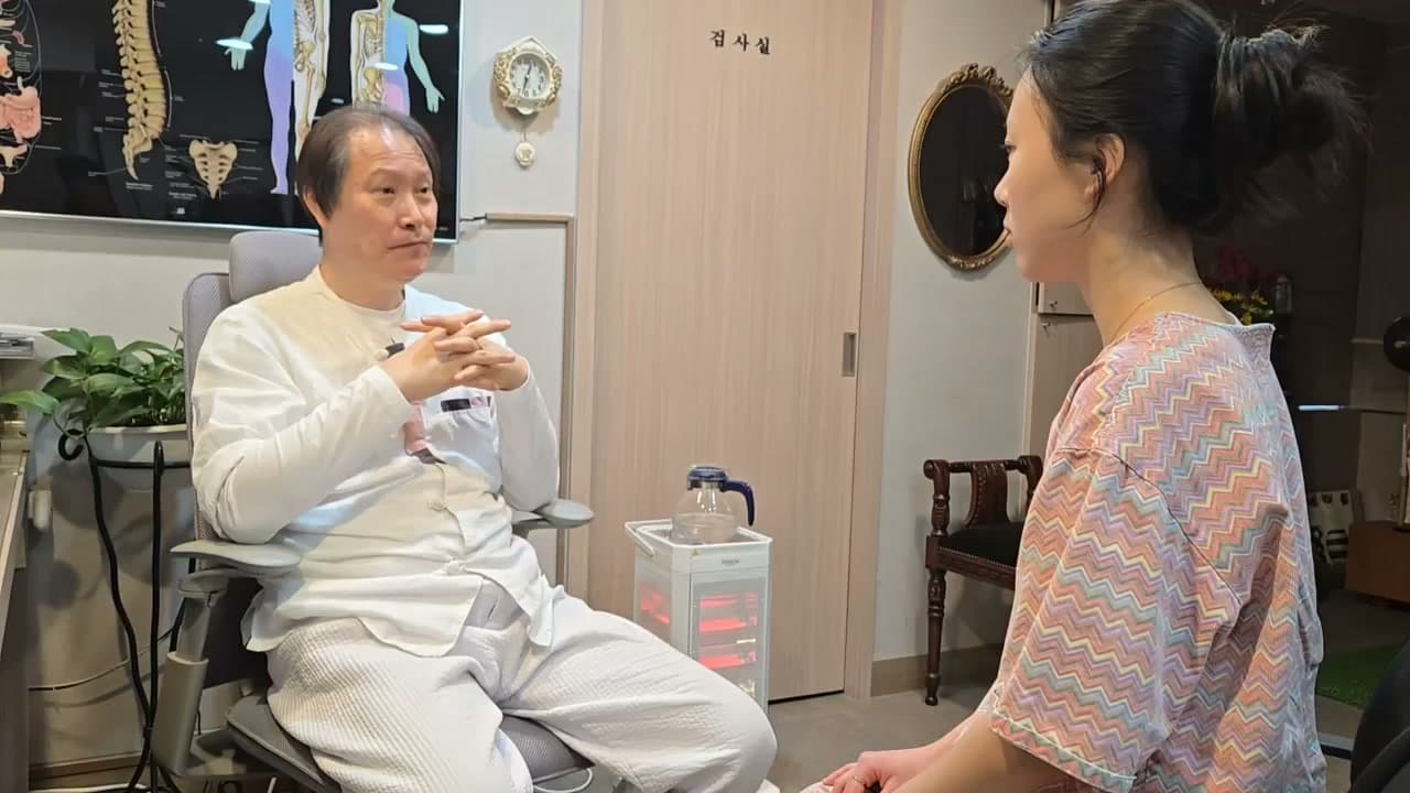 진료실에서 의료진과 환자가 손발의 냉감과 생리 기간의 상태를 이야기하는 장면