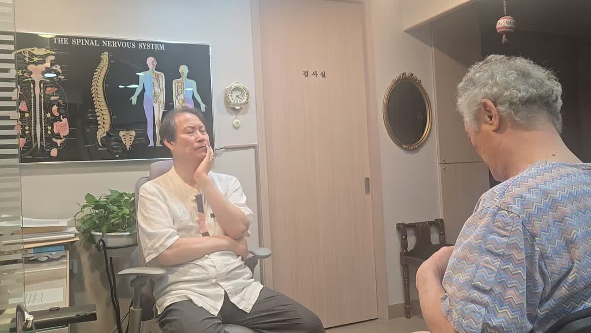 진료실에서 의료진과 환자가 마주 앉아 증상에 관해 이야기하는 장면