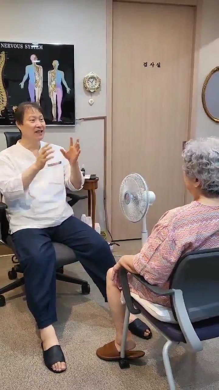 진료실에서 의료진과 82세 환자가 오래된 허리와 다리 통증 및 보행 불편을 상담하는 장면